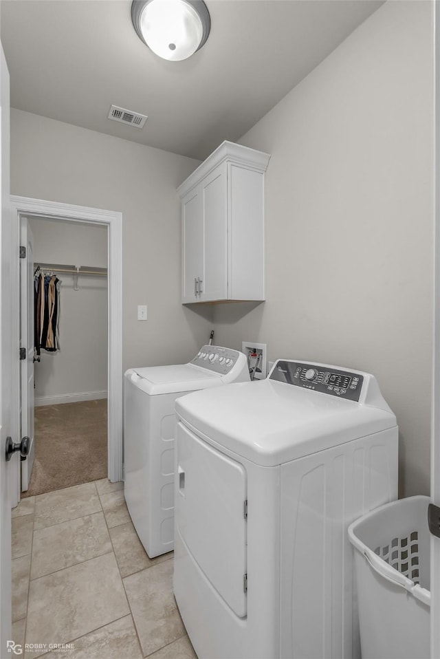 washroom featuring separate washer and dryer, light colored carpet, cabinet space, and visible vents