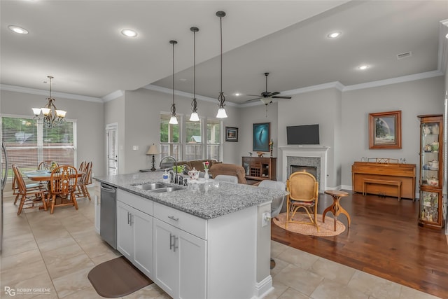kitchen with a kitchen island with sink, stainless steel dishwasher, a sink, ceiling fan with notable chandelier, and a premium fireplace