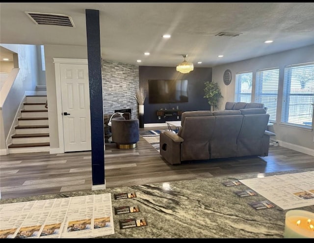 living room with visible vents, stairs, baseboards, and wood finished floors