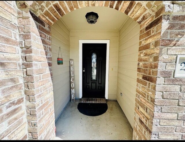 view of exterior entry featuring brick siding