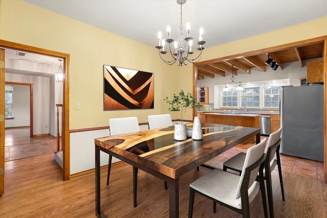 dining room with visible vents, light wood-style flooring, beam ceiling, and a chandelier