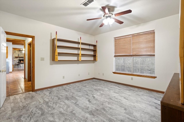 unfurnished room with baseboards, ceiling fan, a fireplace, and visible vents