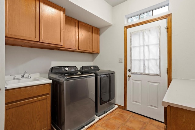 clothes washing area with a sink, light tile patterned floors, cabinet space, and washing machine and clothes dryer