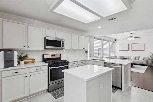 1406 Springmeadow Dr, Allen, TX 75002 - kitchen featuring appliances with stainless steel finishes, a sink, a peninsula, a kitchen island, and light countertops
