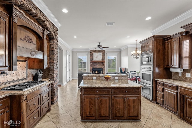 221 Cattail Trl, Benton, LA 71006 - kitchen featuring a fireplace, a center island, tasteful backsplash, a ceiling fan, and stainless steel appliances