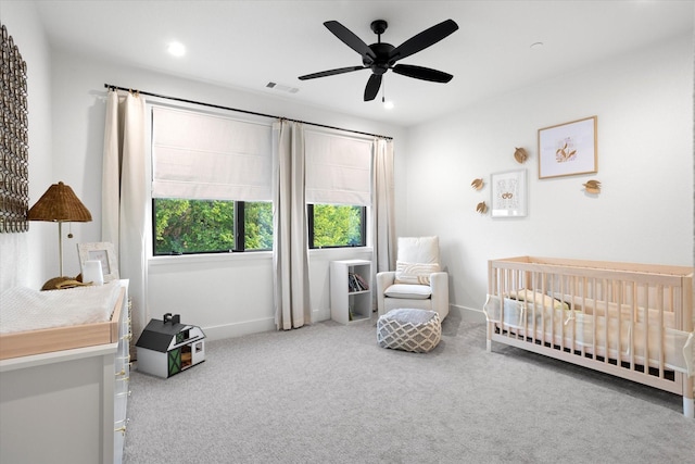 carpeted bedroom featuring ceiling fan, visible vents, a nursery area, baseboards, and recessed lighting