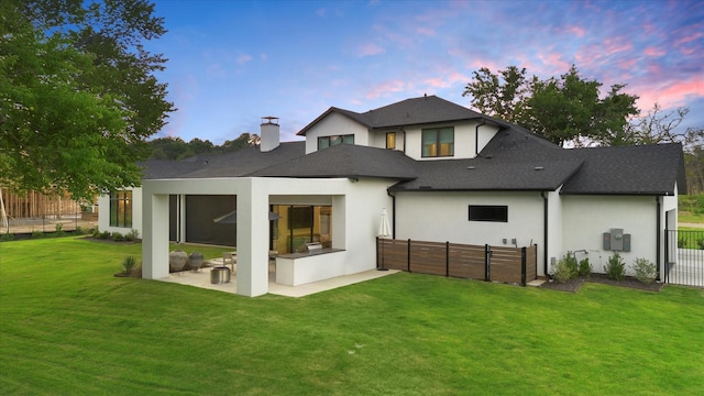 back of property with a fenced backyard, stucco siding, a chimney, a patio area, and a lawn
