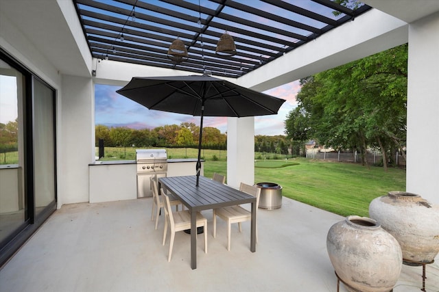 patio terrace at dusk featuring fence, a pergola, outdoor dining space, exterior kitchen, and a lawn