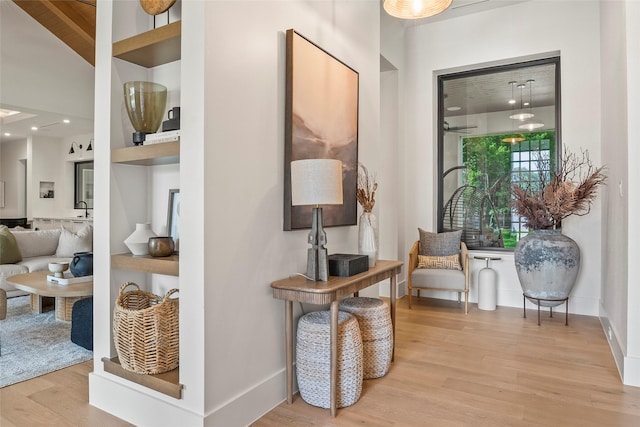 hallway featuring a sink, baseboards, recessed lighting, and wood finished floors