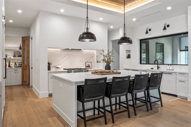 kitchen with light stone counters, a sink, a center island, white cabinetry, and recessed lighting