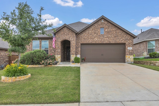 view of front of home featuring driveway, brick siding, a front lawn, an attached garage, and a shingled roof