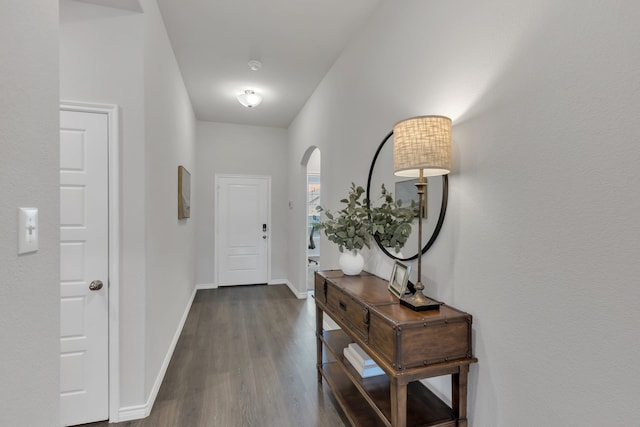 entryway featuring baseboards, dark wood finished floors, and arched walkways