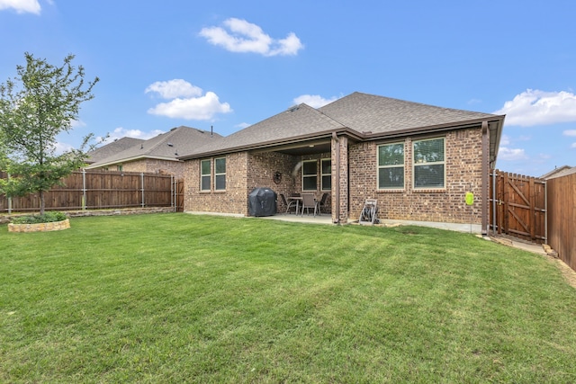 back of property with roof with shingles, brick siding, a fenced backyard, a lawn, and a patio