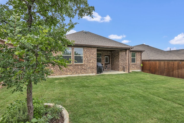 rear view of house featuring a fenced backyard, brick siding, a shingled roof, a patio area, and a yard