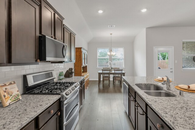kitchen with decorative backsplash, visible vents, a sink, light wood finished floors, and stainless steel appliances