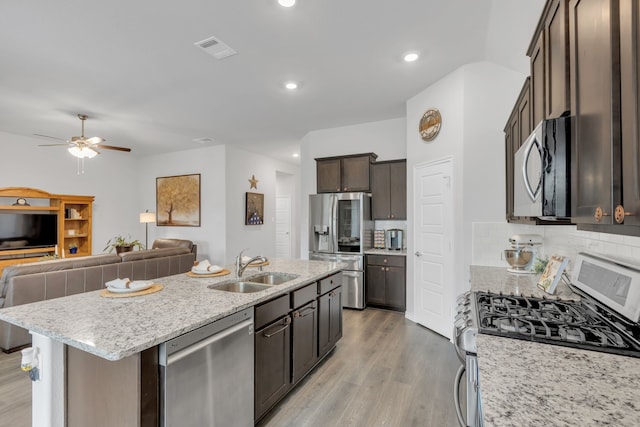 kitchen featuring visible vents, open floor plan, a sink, light wood finished floors, and appliances with stainless steel finishes