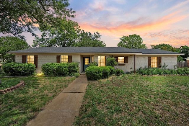 ranch-style house with a yard and brick siding