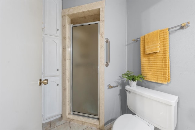 bathroom with tile patterned floors, a stall shower, and toilet