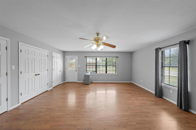 interior space featuring two closets, baseboards, multiple windows, and wood finished floors