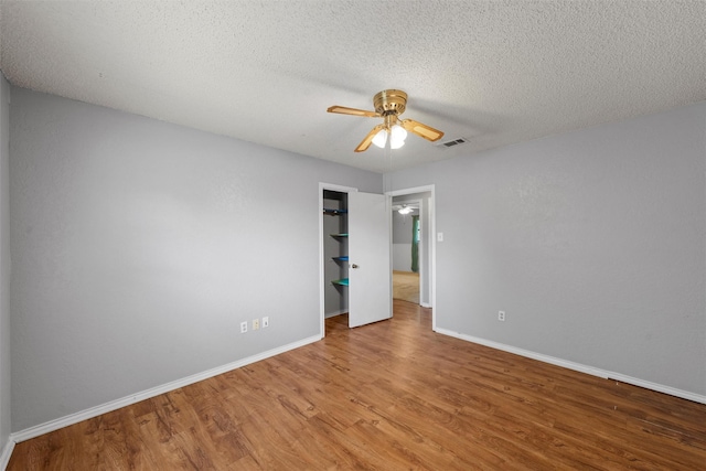 unfurnished room featuring a ceiling fan, baseboards, visible vents, and wood finished floors