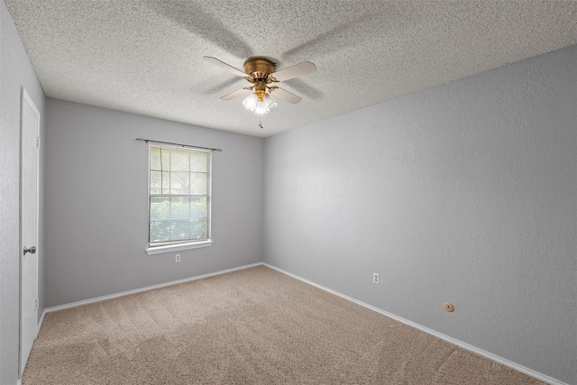 carpeted spare room featuring a textured ceiling, ceiling fan, and baseboards