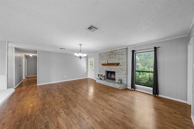 unfurnished living room featuring an inviting chandelier, plenty of natural light, a textured ceiling, and wood finished floors
