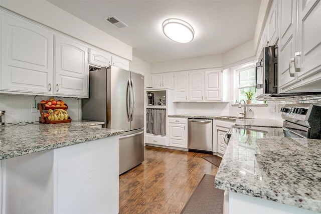 kitchen with visible vents, appliances with stainless steel finishes, tasteful backsplash, light stone countertops, and wood finished floors