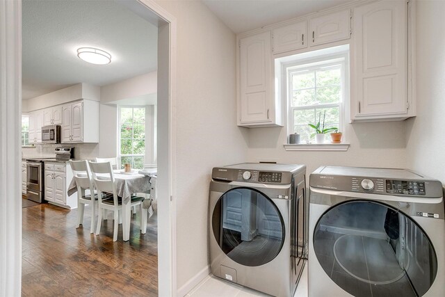 clothes washing area with baseboards, dark wood-style flooring, cabinet space, and washer and clothes dryer