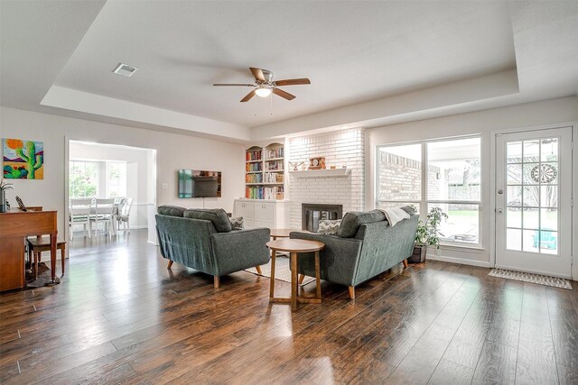 living room with visible vents, a ceiling fan, a raised ceiling, and dark wood-style flooring