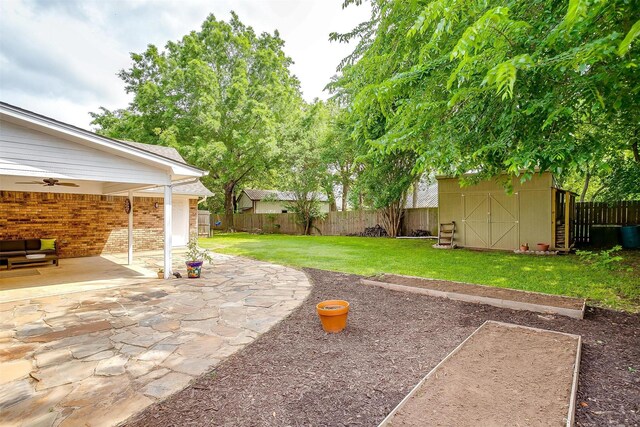 view of yard featuring a fenced backyard, a ceiling fan, an outdoor structure, and a patio area