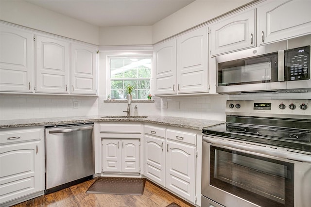 kitchen featuring a sink, decorative backsplash, appliances with stainless steel finishes, and white cabinetry