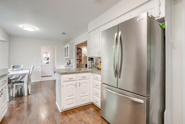 kitchen with white cabinets, freestanding refrigerator, a peninsula, dark wood-style floors, and glass insert cabinets