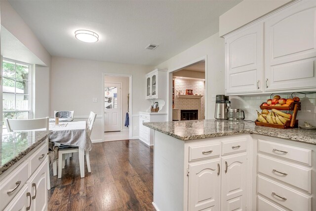 kitchen with visible vents, dark wood-style flooring, backsplash, and white cabinets
