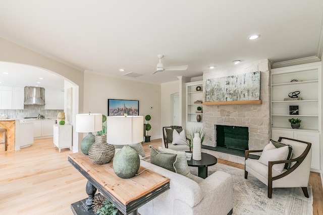 300 Preakness Cir, Southlake, TX 76092 - living area featuring crown molding, light wood-type flooring, arched walkways, a ceiling fan, and a fireplace