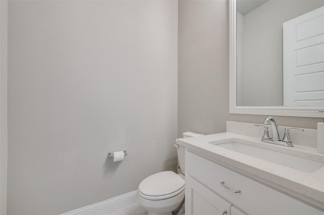 half bath with toilet, baseboards, and vanity
