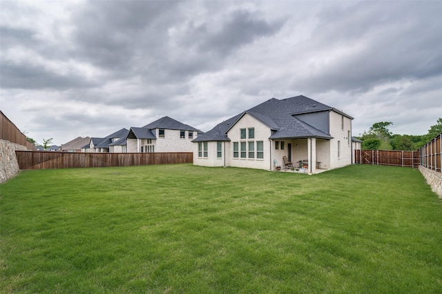 back of property featuring a lawn, a shingled roof, a fenced backyard, and a patio area