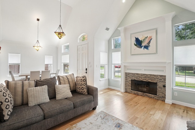 living area featuring high vaulted ceiling, baseboards, wood finished floors, and visible vents