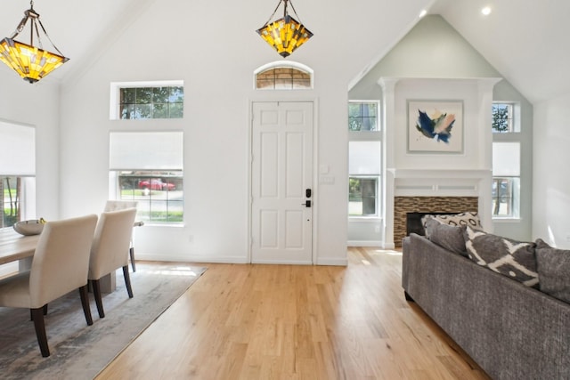entrance foyer with high vaulted ceiling, baseboards, light wood finished floors, and a wealth of natural light
