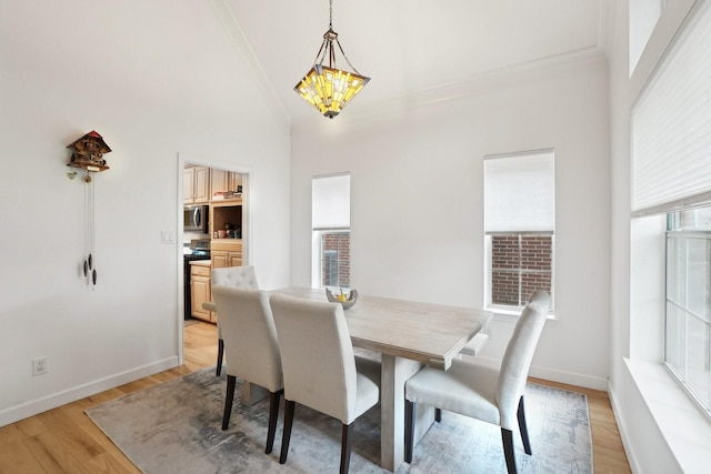 dining space with an inviting chandelier, light wood finished floors, baseboards, lofted ceiling, and ornamental molding