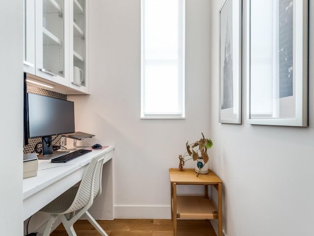 office with built in study area, baseboards, and wood finished floors