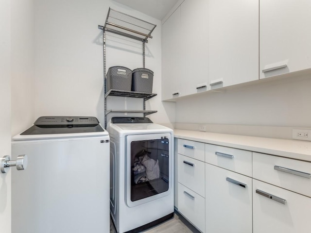 laundry room with separate washer and dryer and cabinet space
