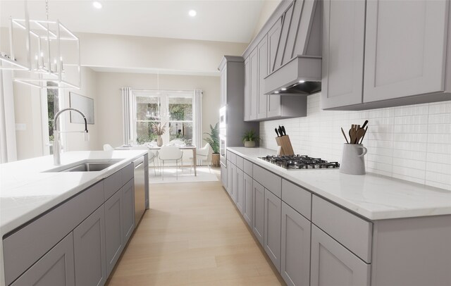 kitchen featuring a sink, premium range hood, stainless steel appliances, backsplash, and gray cabinetry
