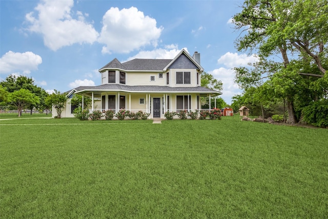 view of front of property featuring a shingled roof, a front yard, covered porch, and a chimney