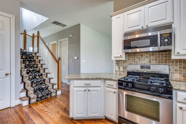 kitchen featuring visible vents, white cabinets, light wood finished floors, appliances with stainless steel finishes, and backsplash