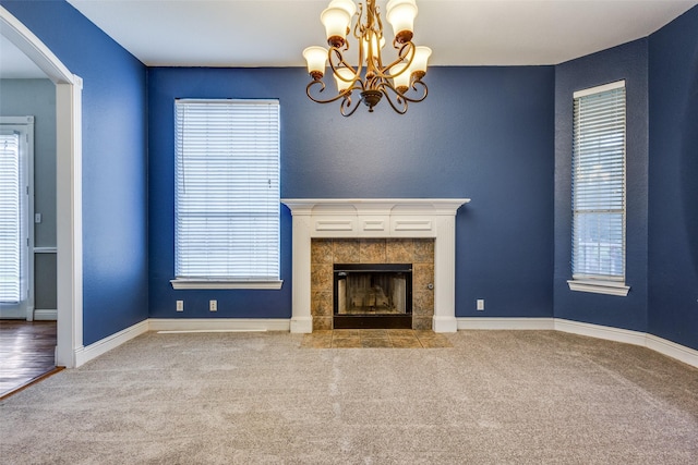 unfurnished living room with a wealth of natural light, carpet flooring, and a chandelier