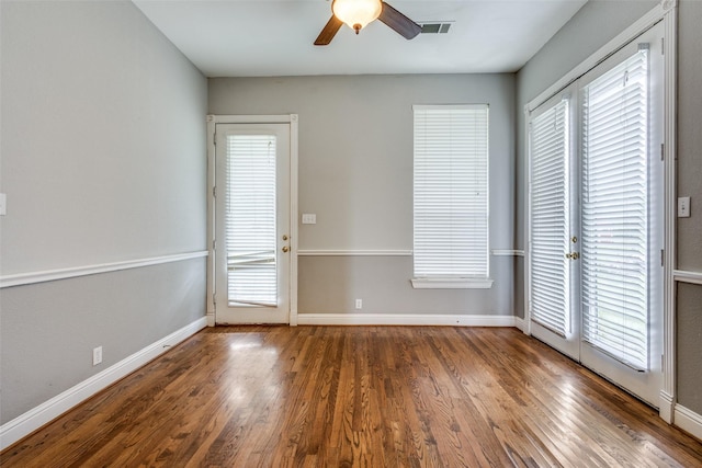 unfurnished room featuring baseboards, ceiling fan, visible vents, and wood finished floors