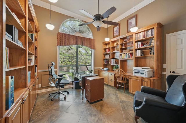 office with ceiling fan, crown molding, built in desk, a wainscoted wall, and a high ceiling