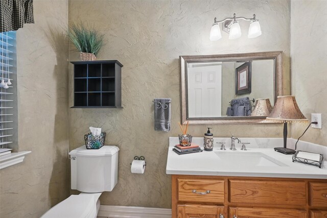 bathroom featuring vanity, baseboards, and toilet