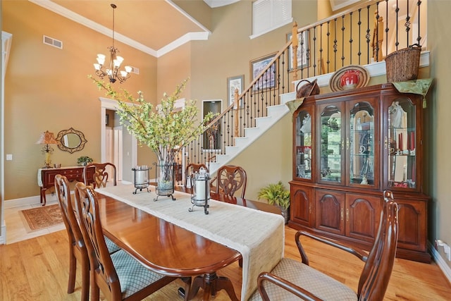 dining room with visible vents, crown molding, stairway, baseboards, and a high ceiling