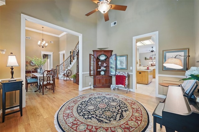 entryway featuring a high ceiling, visible vents, light wood finished floors, and ceiling fan with notable chandelier